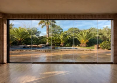 Cortinas de cristal sin perfiles en terraza con vistas a jardín y piscina