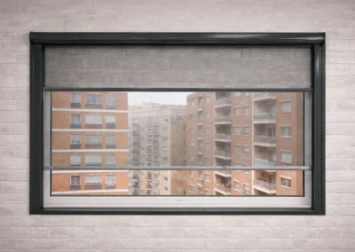 Mosquitera enrollable instalada en ventana con vista exterior a edificios