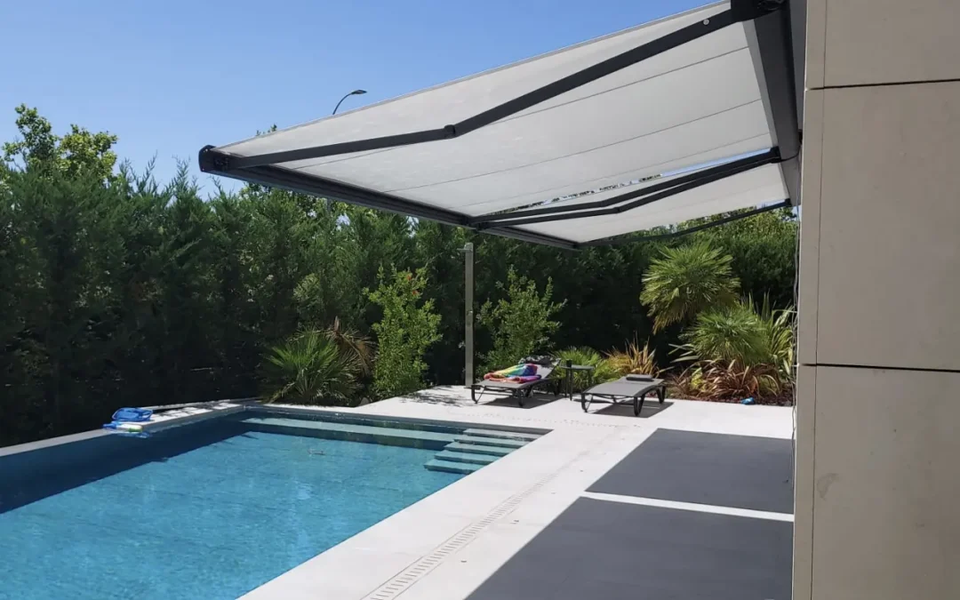 Toldo extensible con cofre instalado junto a piscina en vivienda, ofreciendo sombra y protección solar en exterior