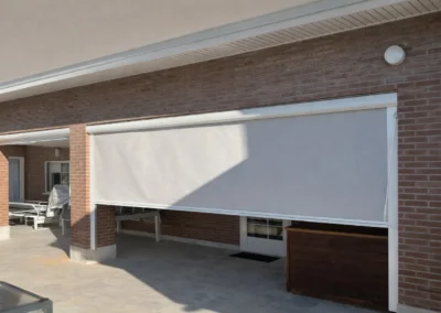 Toldo vertical con cofre instalado en porche exterior de vivienda unifamiliar con estructura de ladrillo